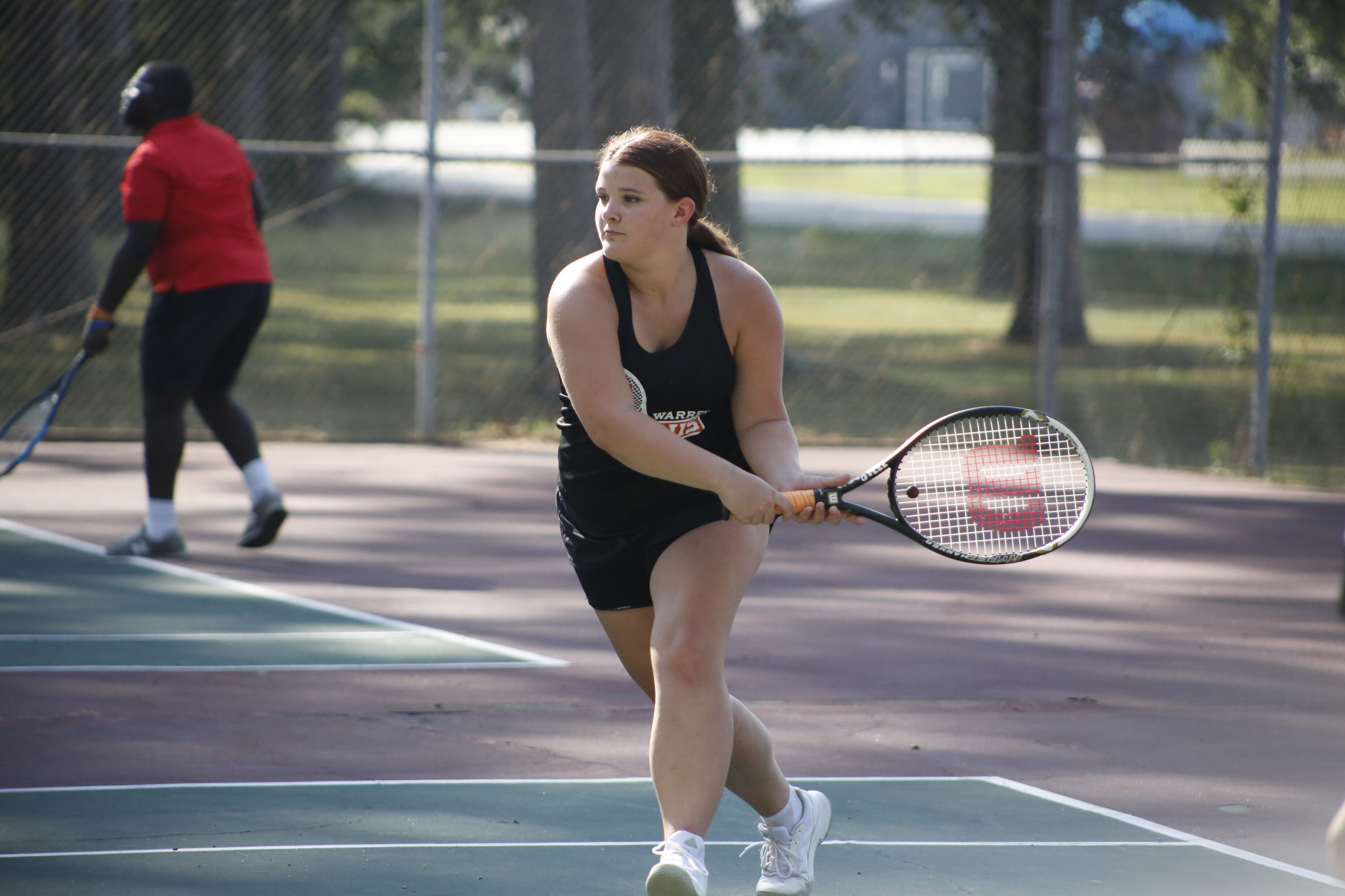 A woman swinging at the ball with her tennis racket.
