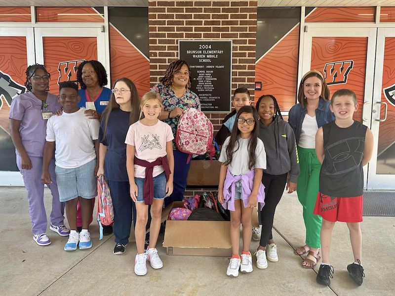A group of people standing in front of a brick wall.