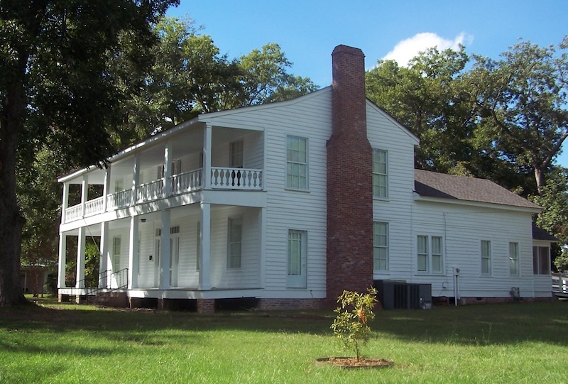 A white house with a tall brick chimney.