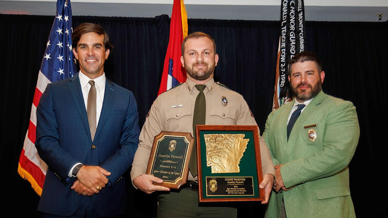 Three men in suits and ties holding awards.