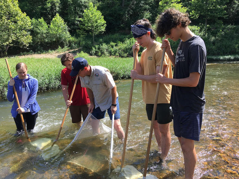 A group of people standing in the water with nets.