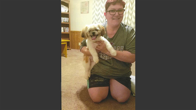 A woman holding a dog in her lap.