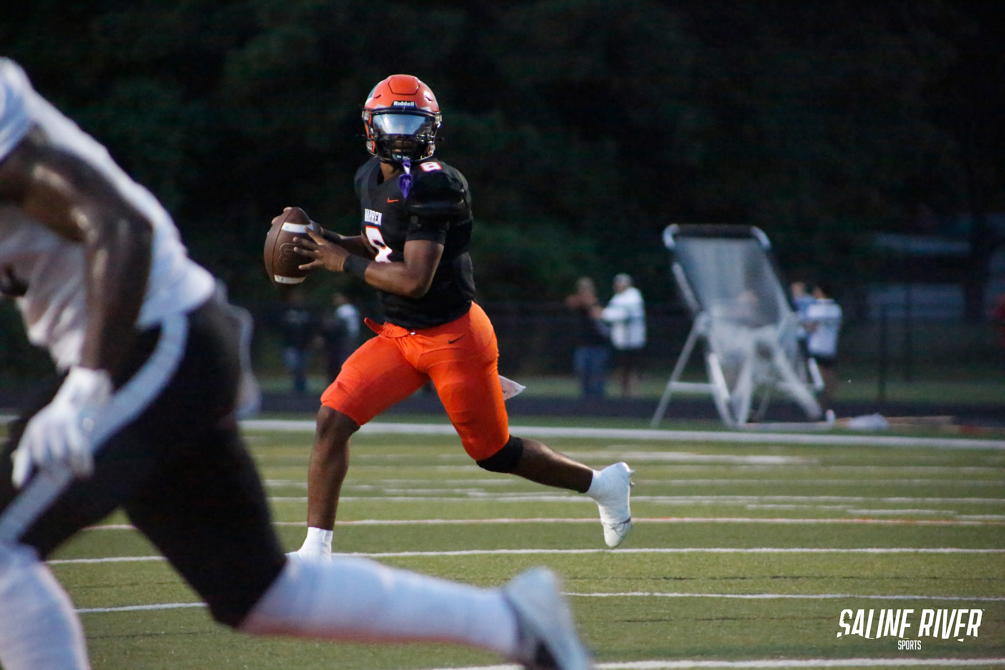 A football player running with the ball in his hand.