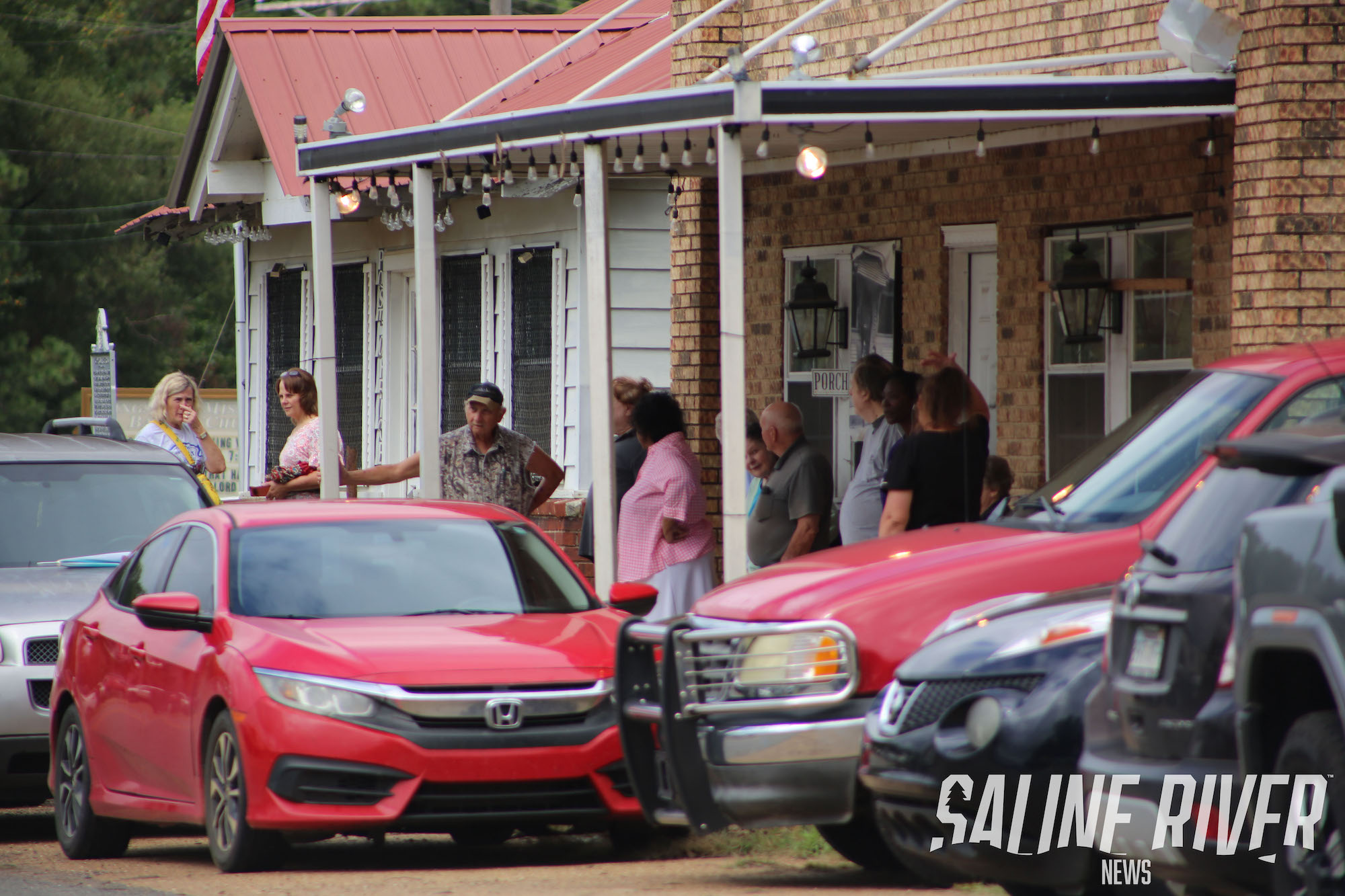 A group of people standing around parked cars.