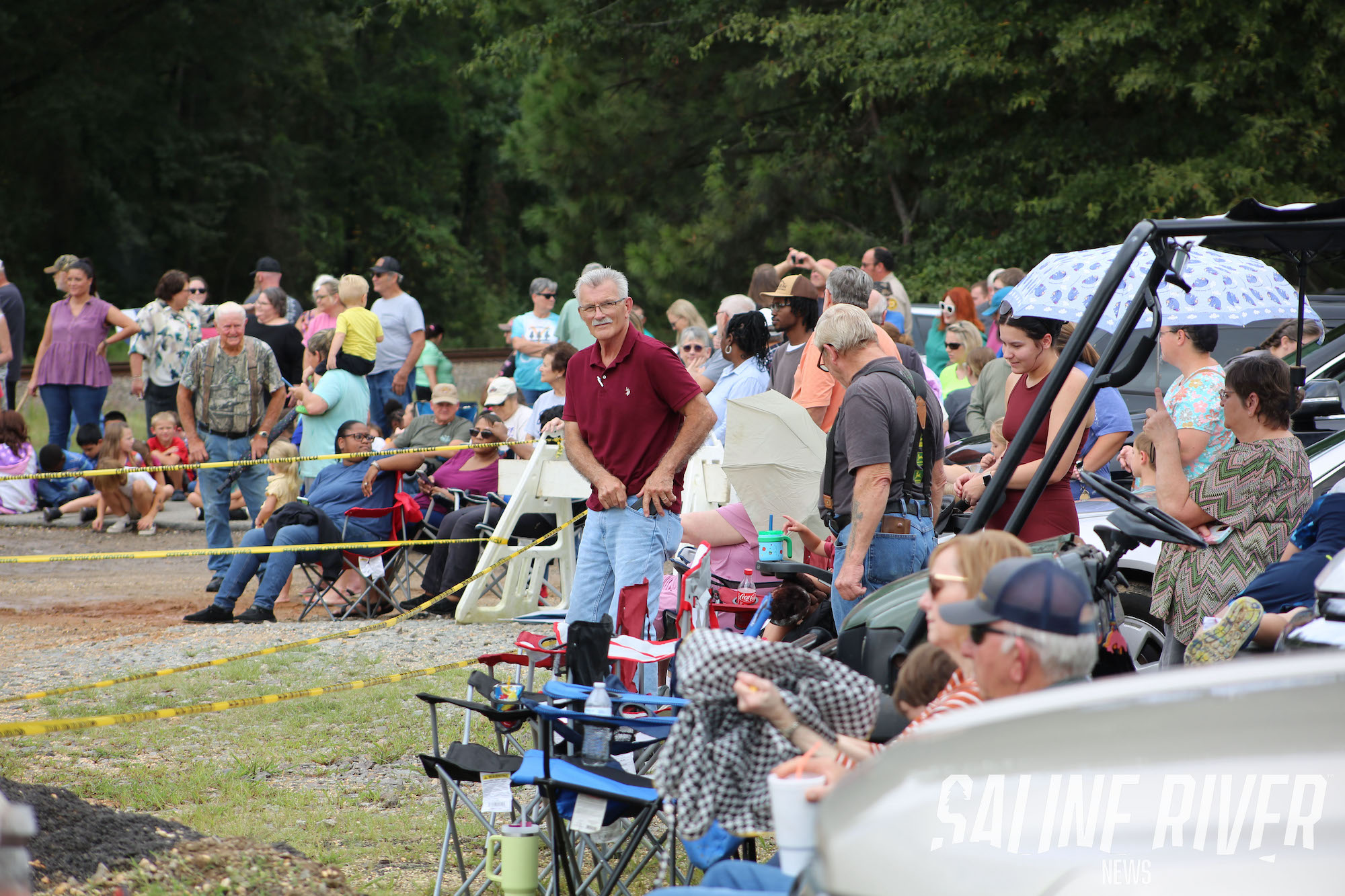 A crowd of people sitting on chairs in the grass.