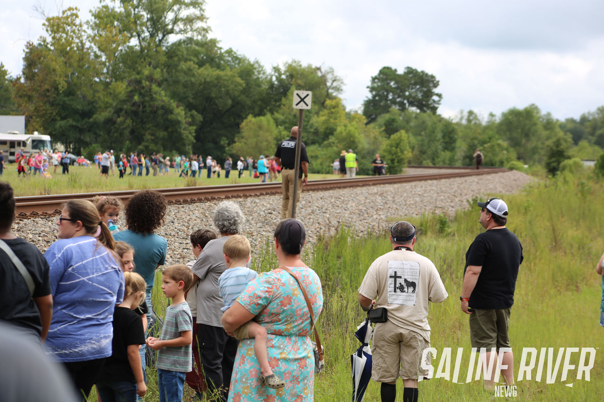 A group of people standing on the side of a train track.