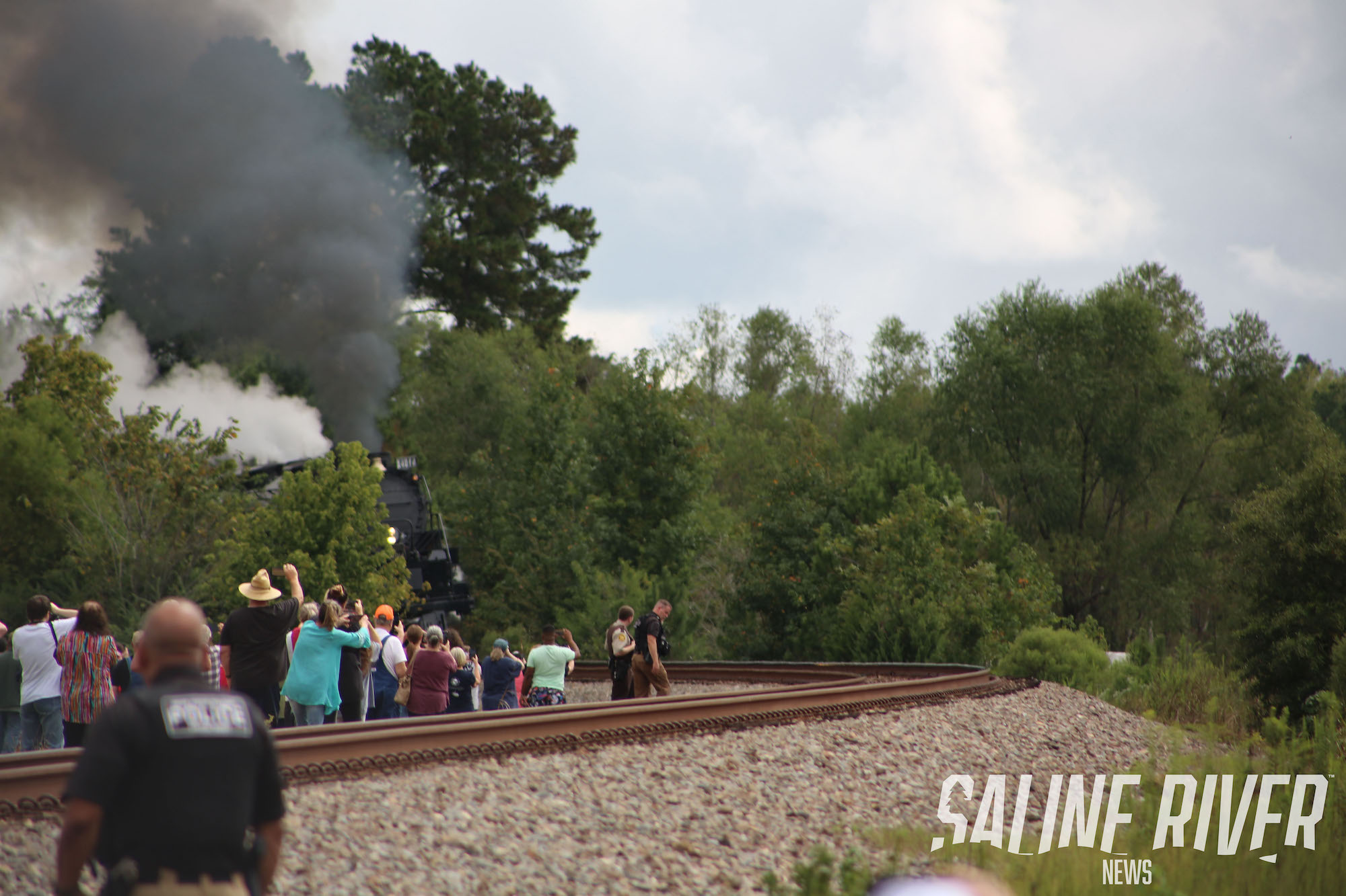 A train on the tracks with people standing around.