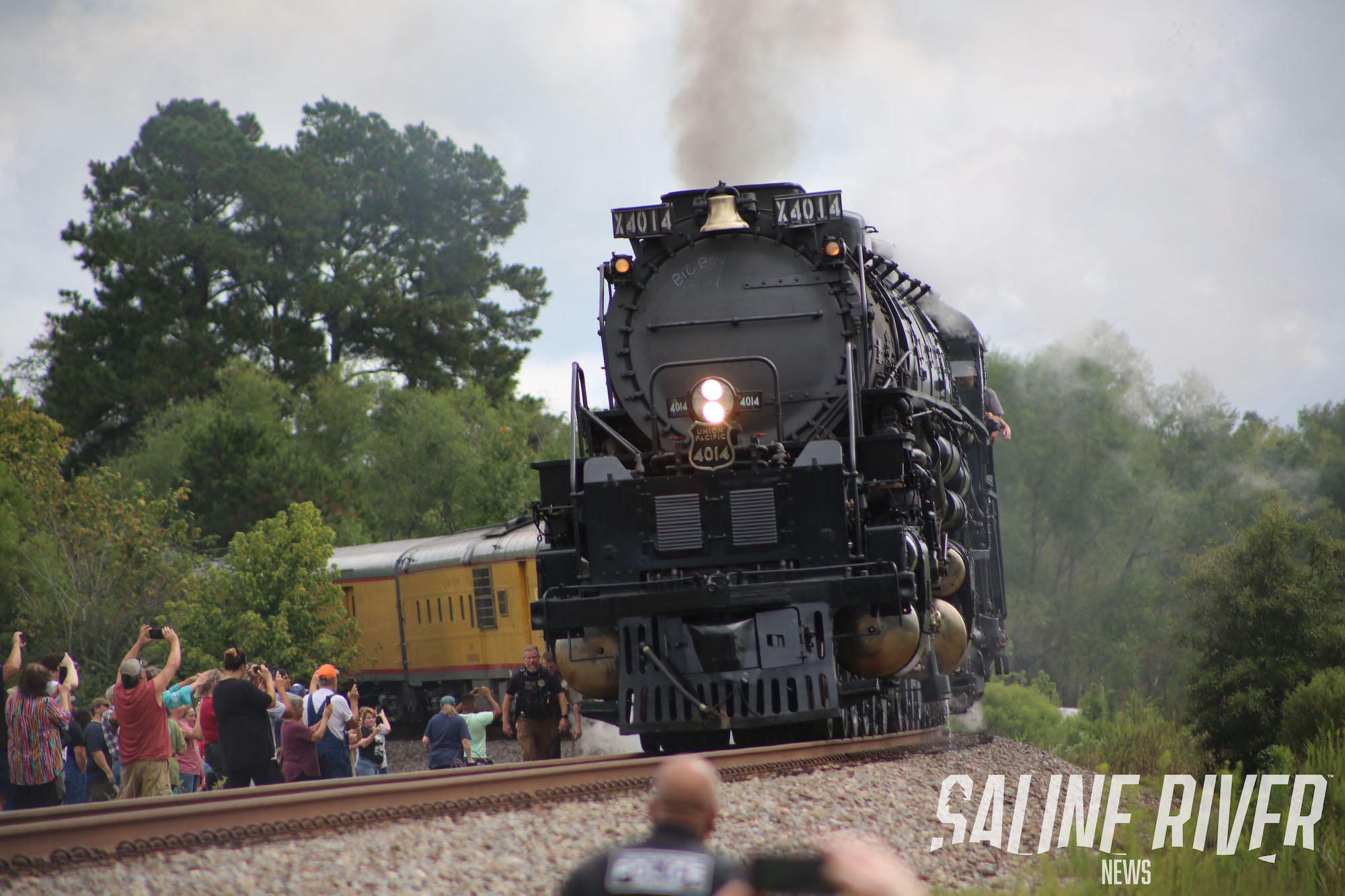 A train is coming down the tracks with people watching.