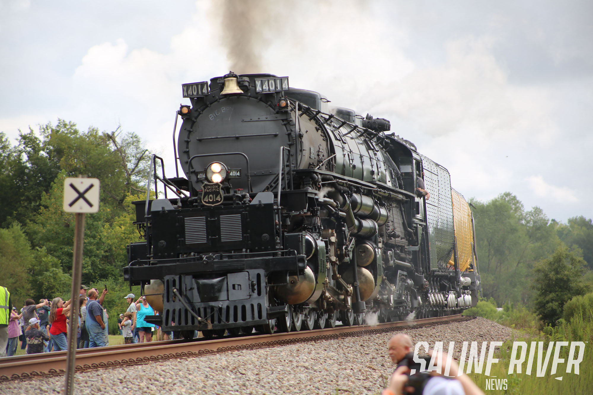 A train is on the tracks with people standing around.