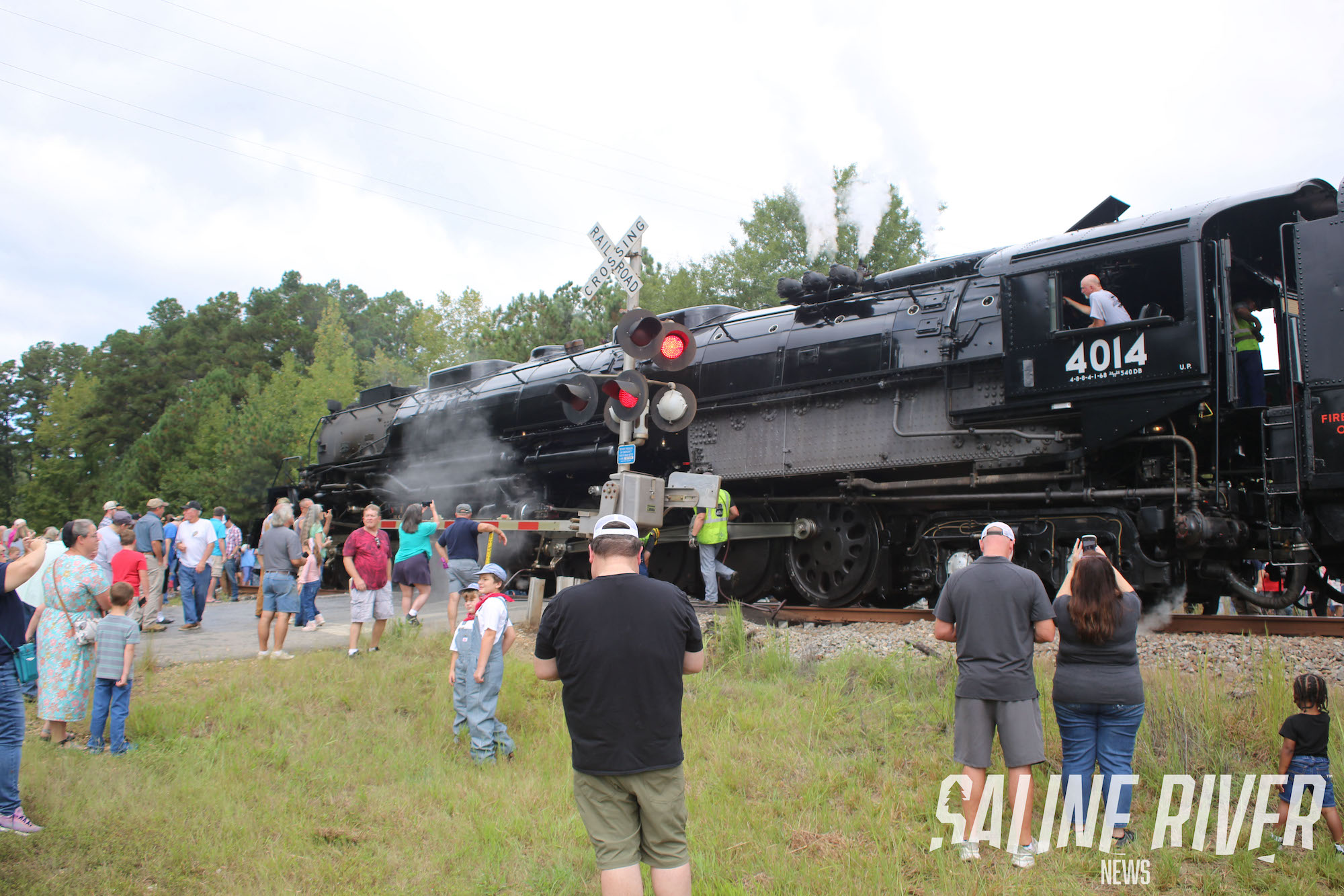 A train is stopped on the tracks as people watch.