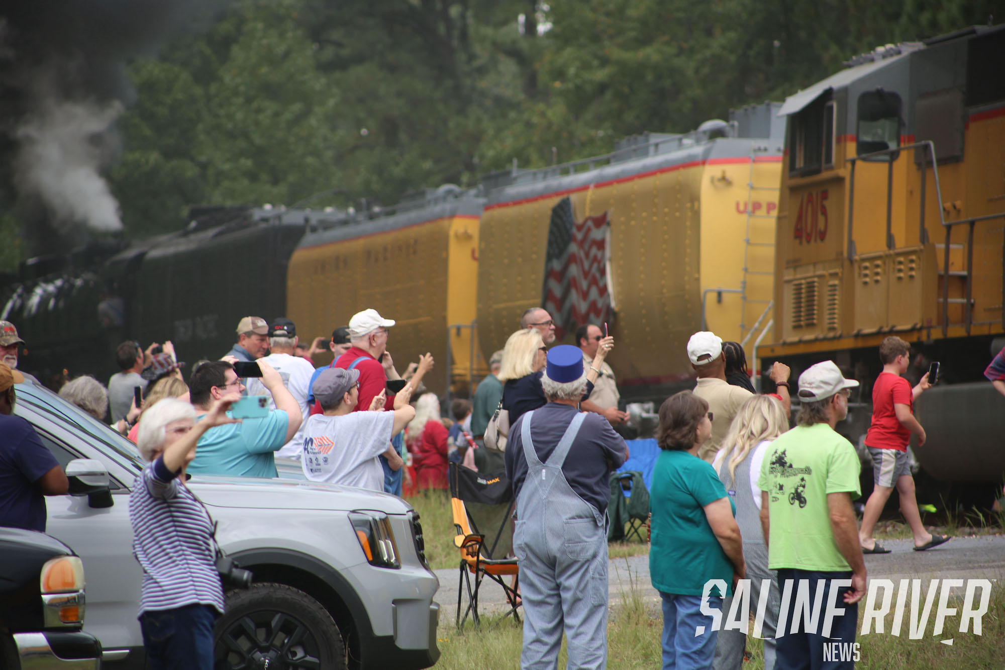 A group of people standing around in front of train cars.