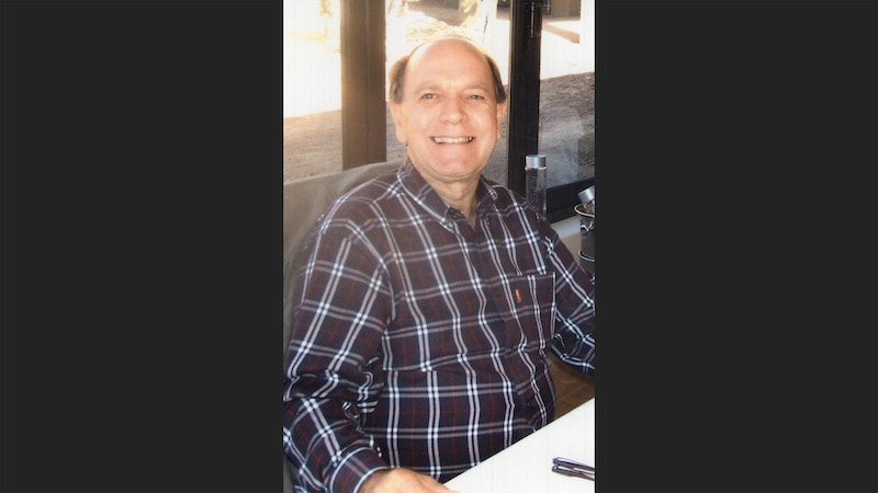 A man sitting at a table smiling for the camera.