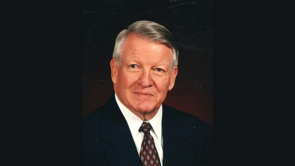 A man in suit and tie with white hair.
