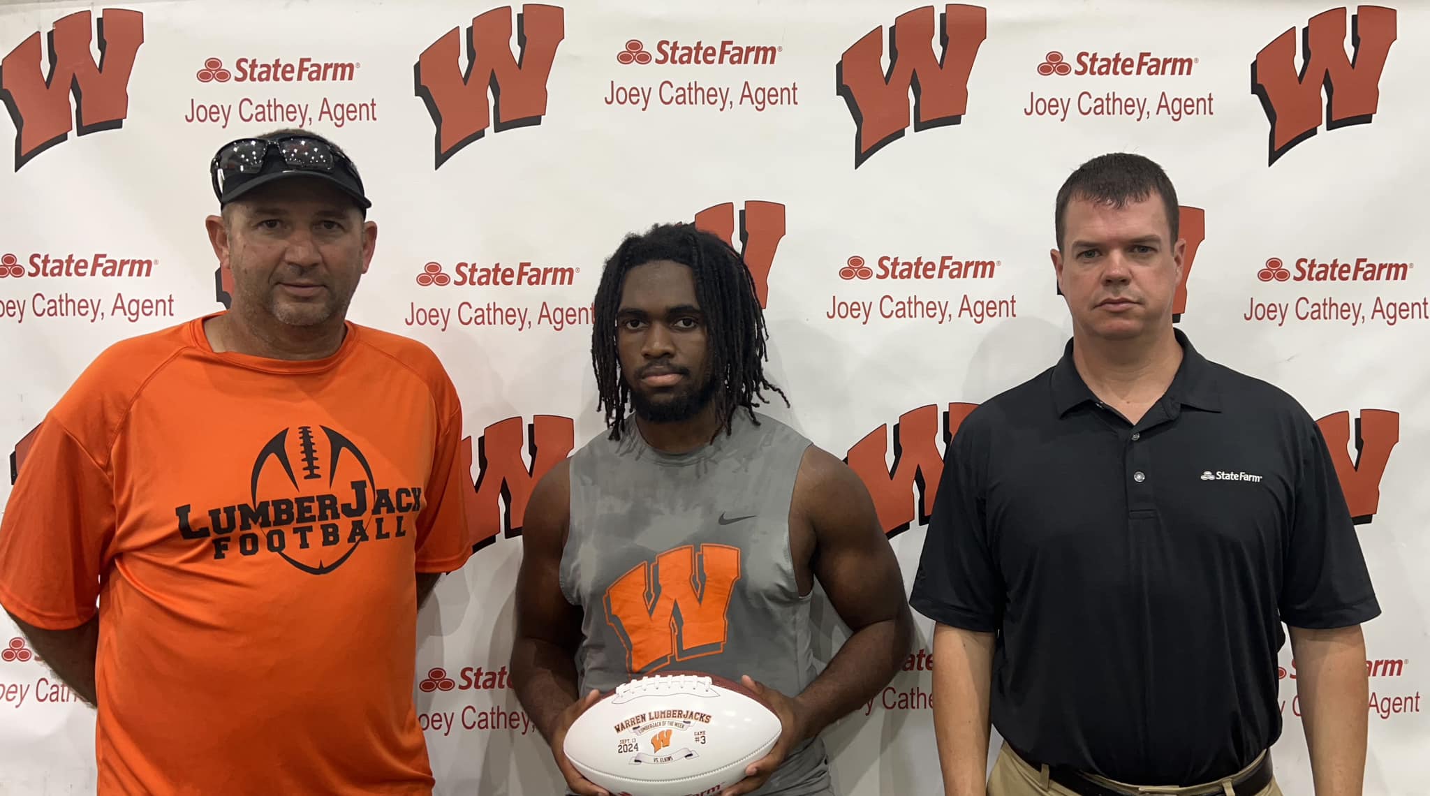 Three men standing in front of a wall with a football.