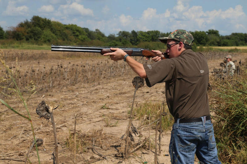 A man is holding a gun in the field