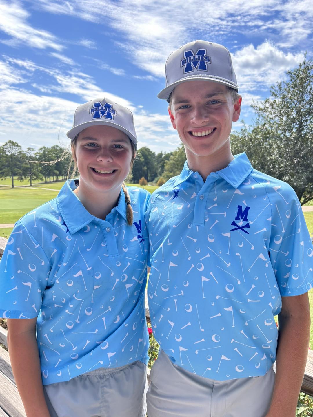 Two young people wearing matching blue shirts and hats.