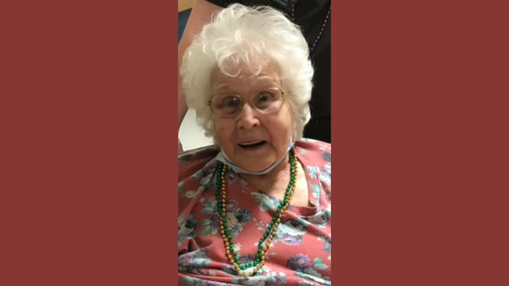 A woman with white hair wearing glasses and a necklace.