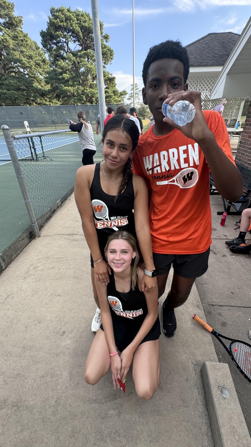 Three people posing for a picture on the tennis court.
