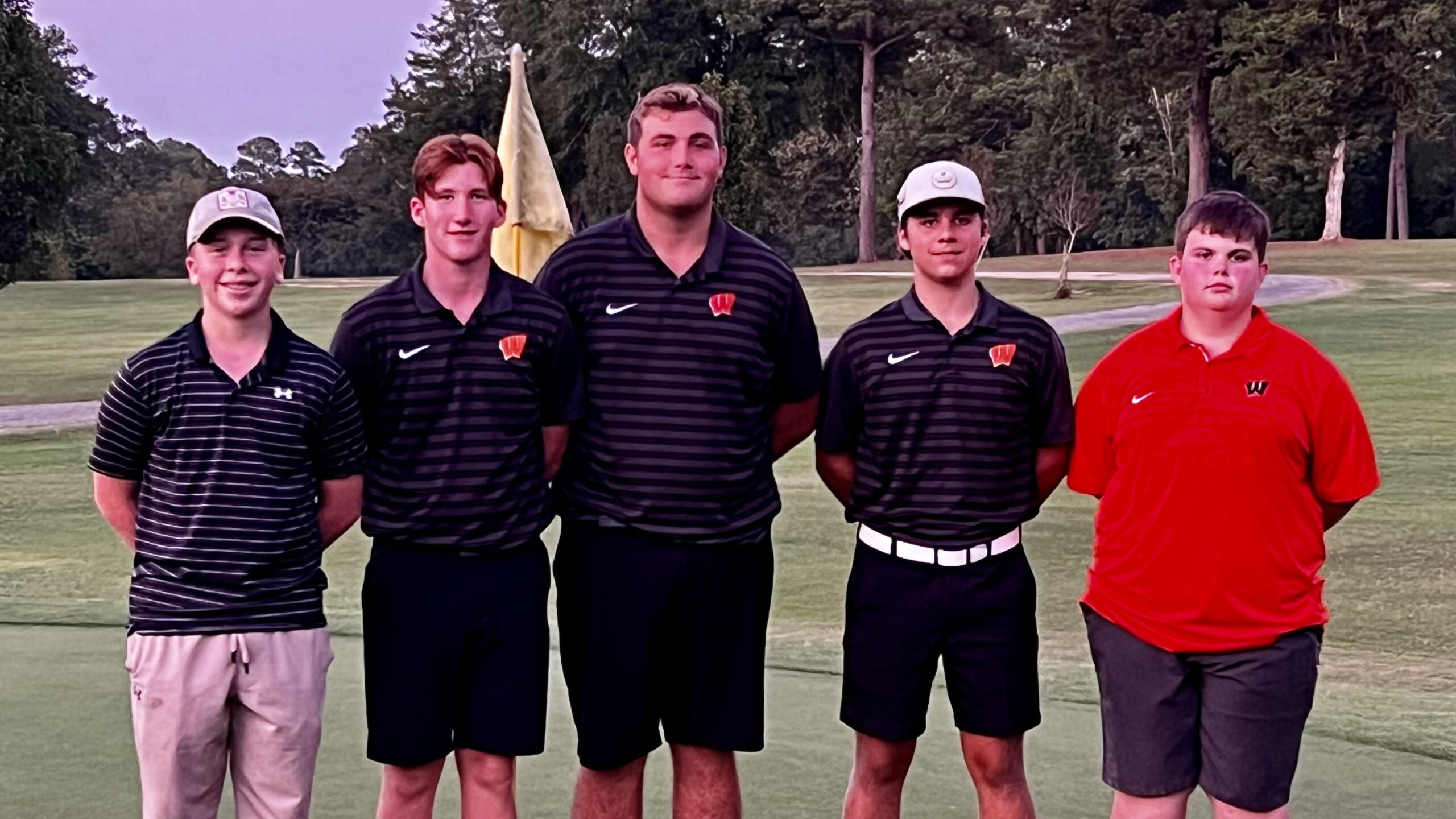 A group of men standing on top of a golf course.