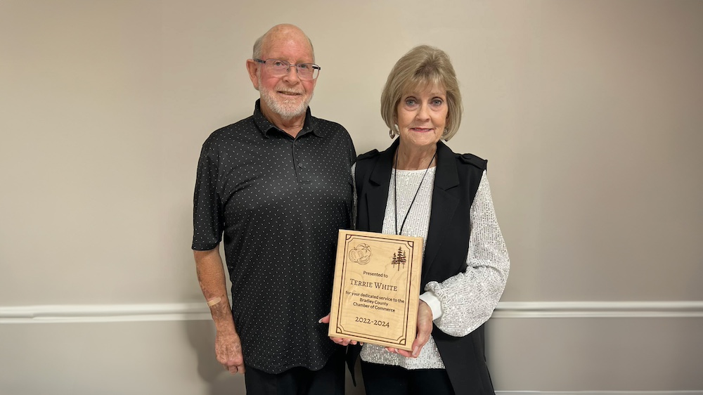 A man and woman holding an award.