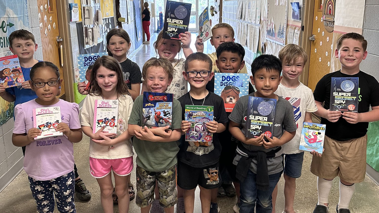 A group of children holding books in their hands.