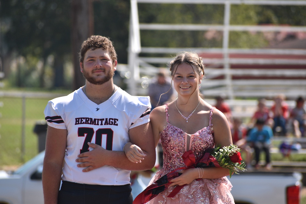 A man and woman in football uniforms holding flowers.