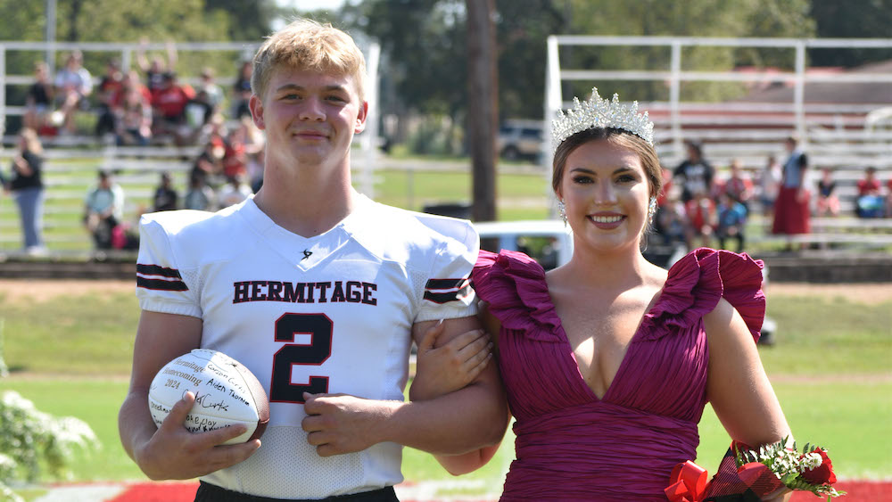 A man and woman in formal wear holding a football.