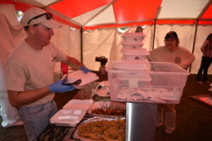 A man standing in front of trays of food.