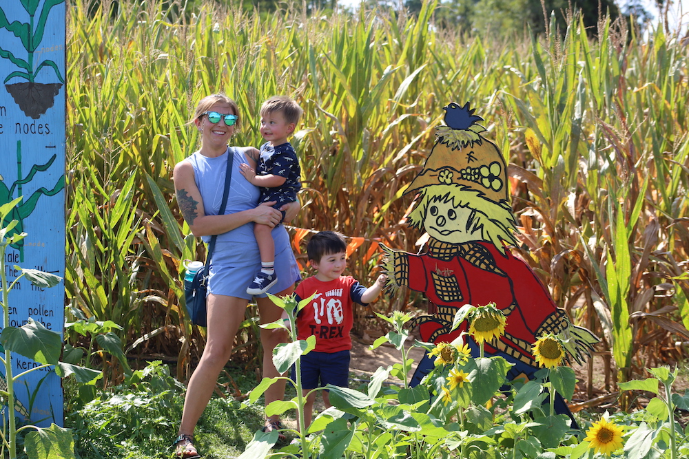 A woman holding a child and standing in the middle of a field.