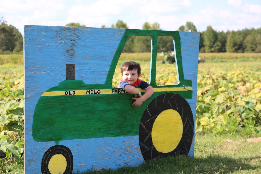 A young boy leaning on the side of a tractor.