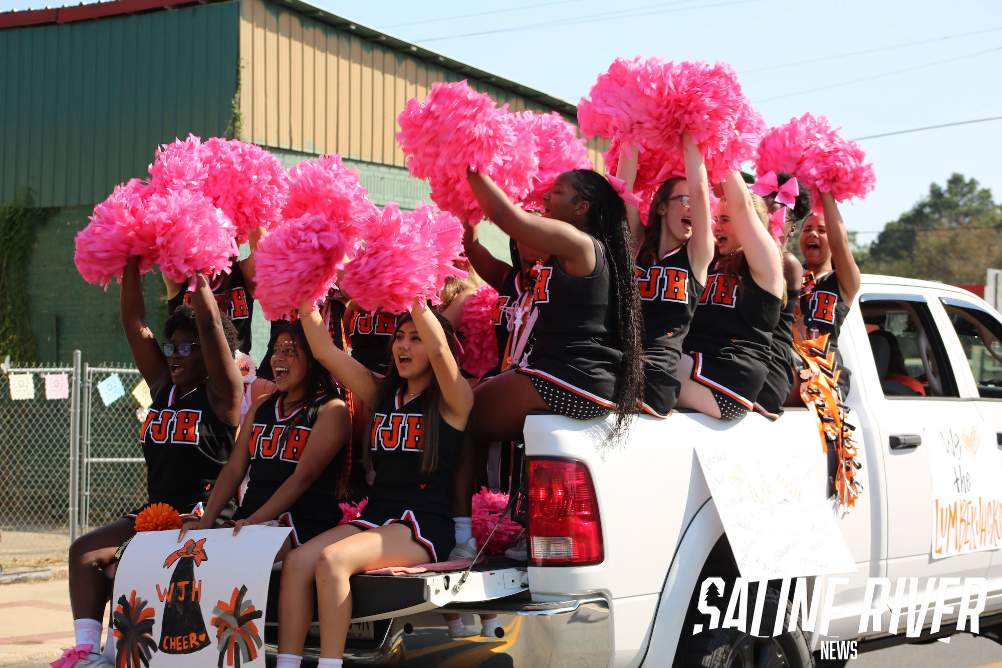 A group of cheerleaders in the back of a truck.