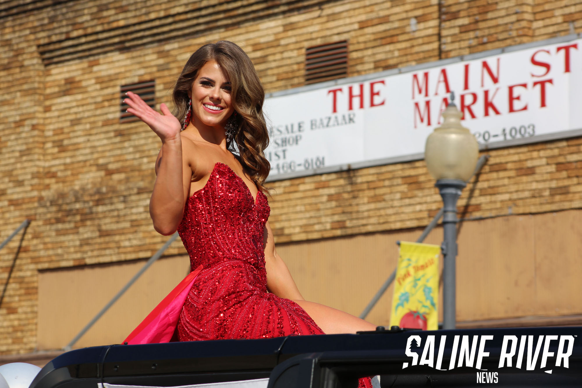 A woman in red dress waving at the crowd.