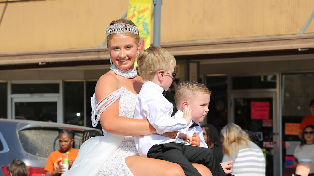 A woman in white dress holding two boys.