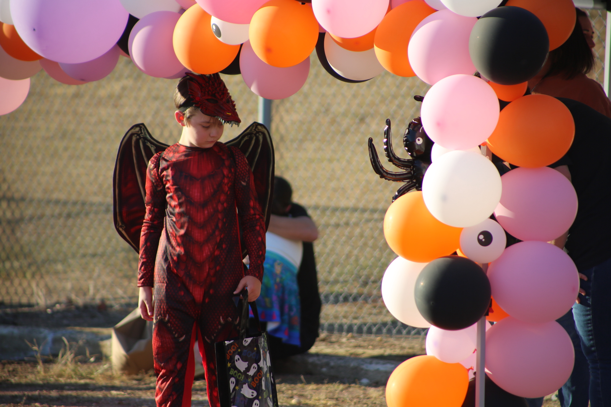 A boy in costume standing under an arch of balloons.