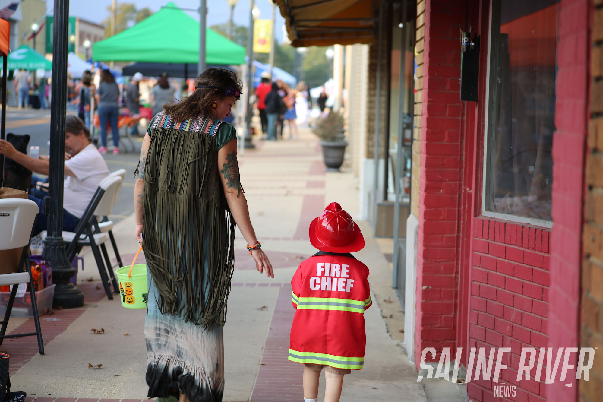A woman and child dressed in costumes on the sidewalk.