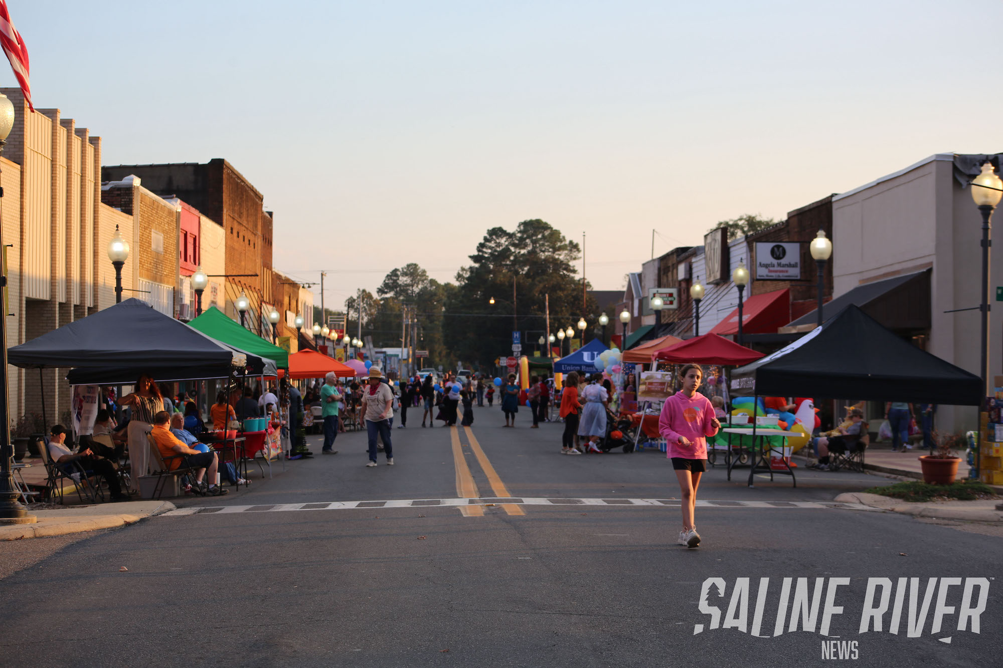 A street filled with people walking and sitting.