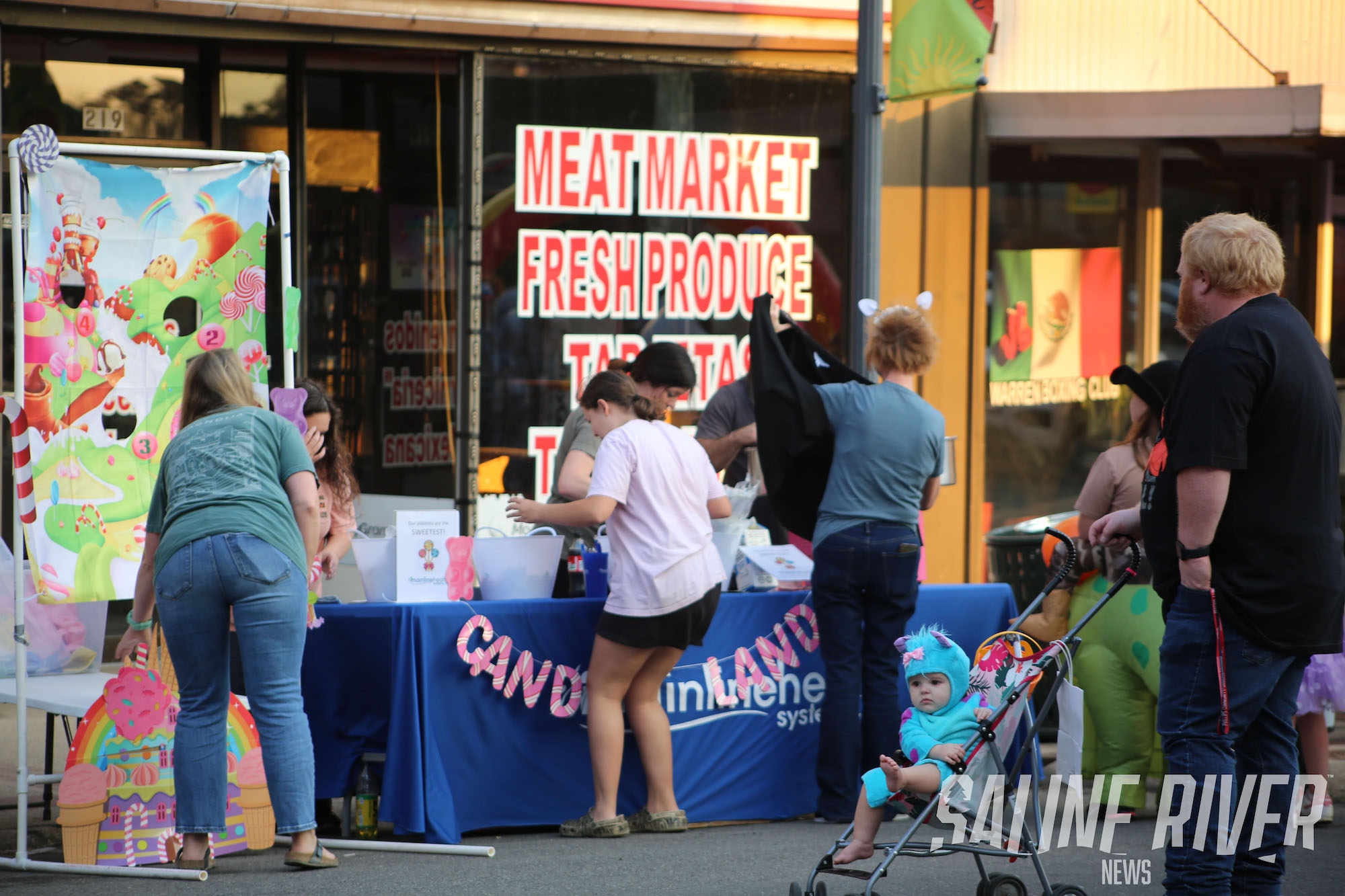 A group of people standing around a meat market.