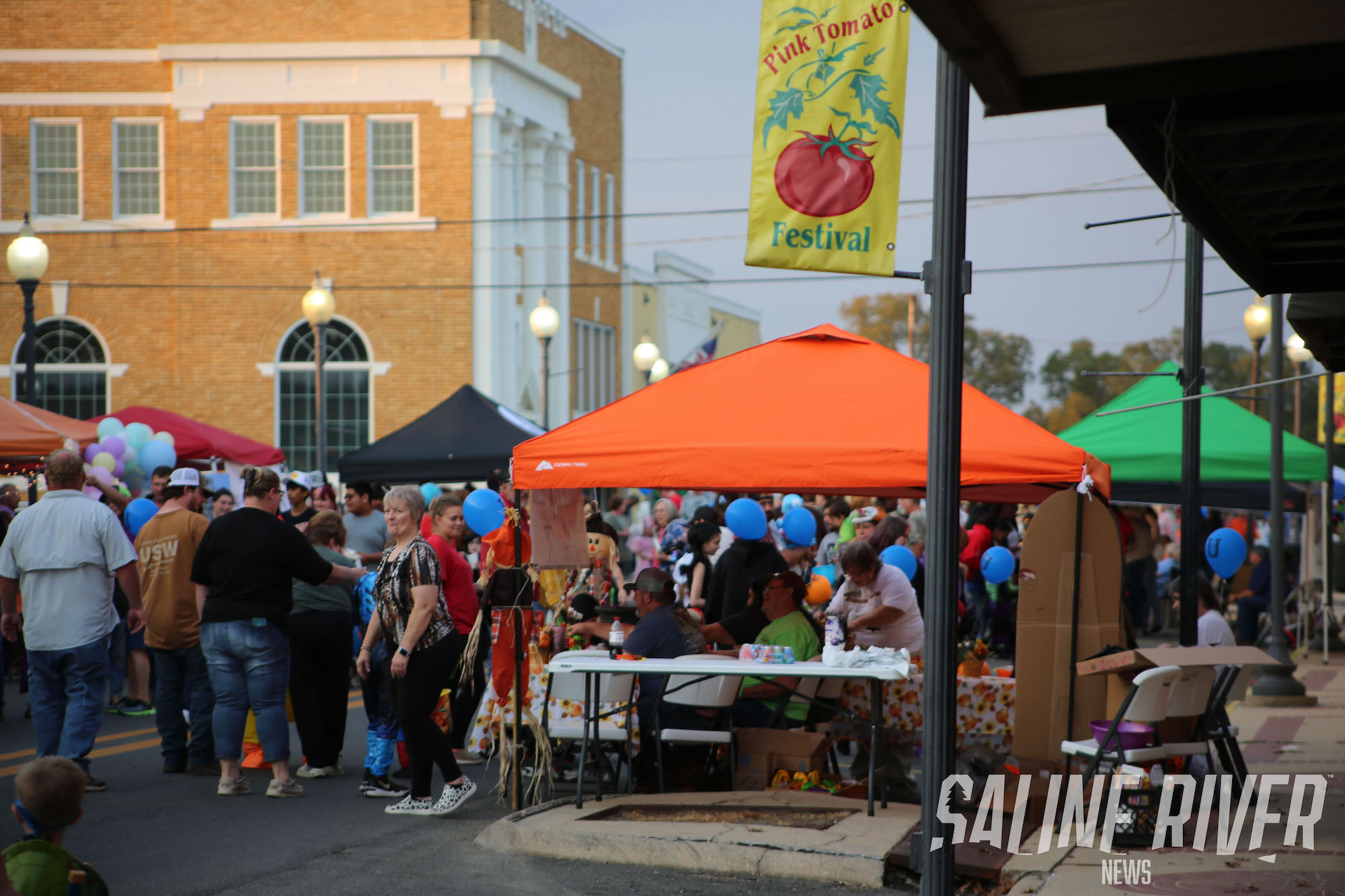 A crowd of people standing around an outdoor market.