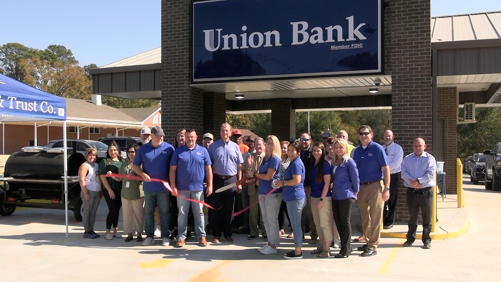 A group of people standing outside of an union bank.