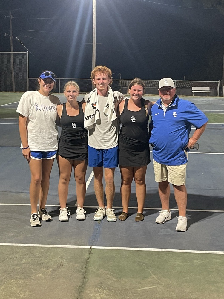 A group of people standing on top of a tennis court.