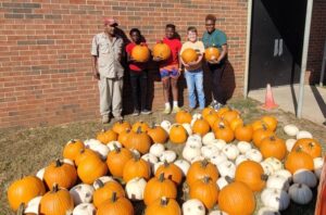 A group of people standing around pumpkins.