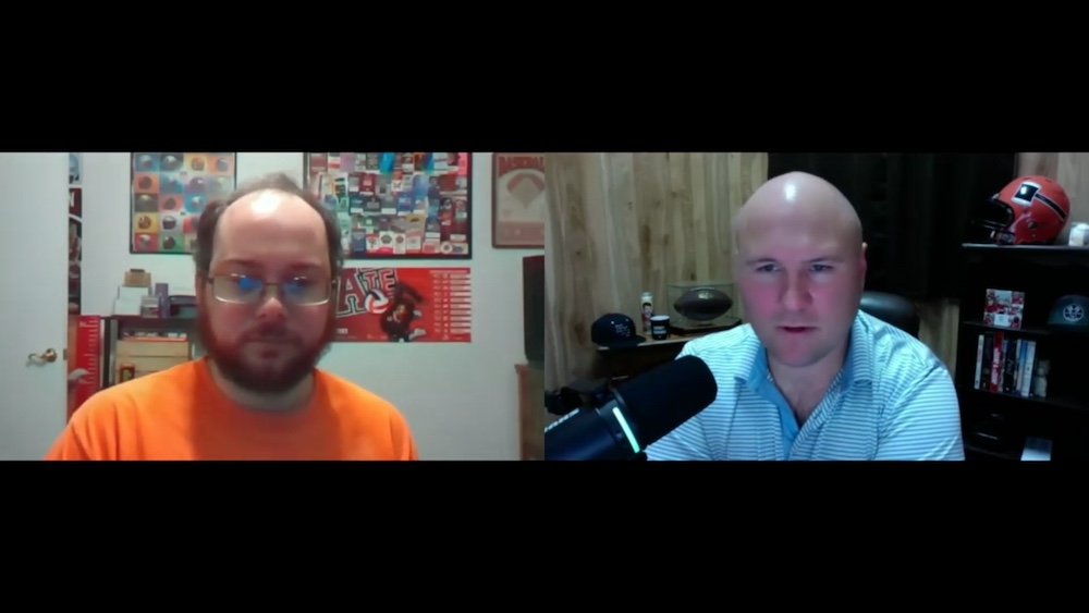 Two men are sitting in front of a microphone.