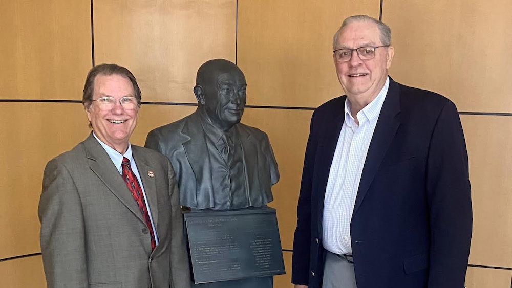 Two men standing next to a statue of a man.