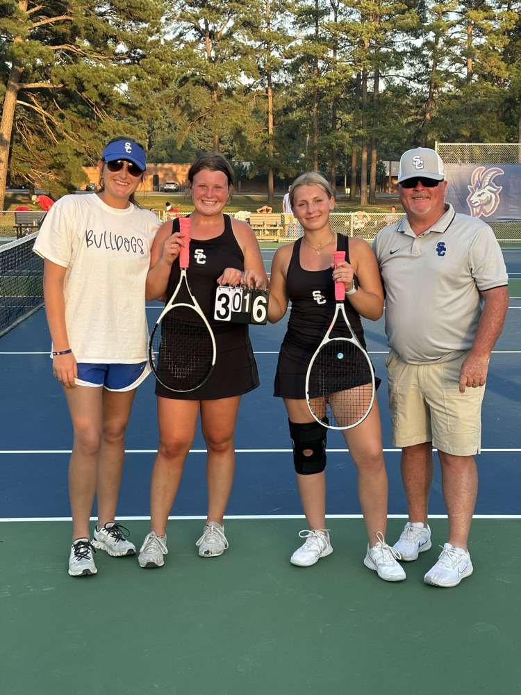 A group of people standing on top of a tennis court.