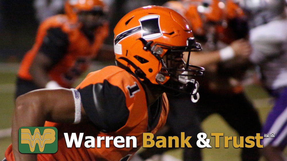 A football player wearing an orange helmet and holding a ball.