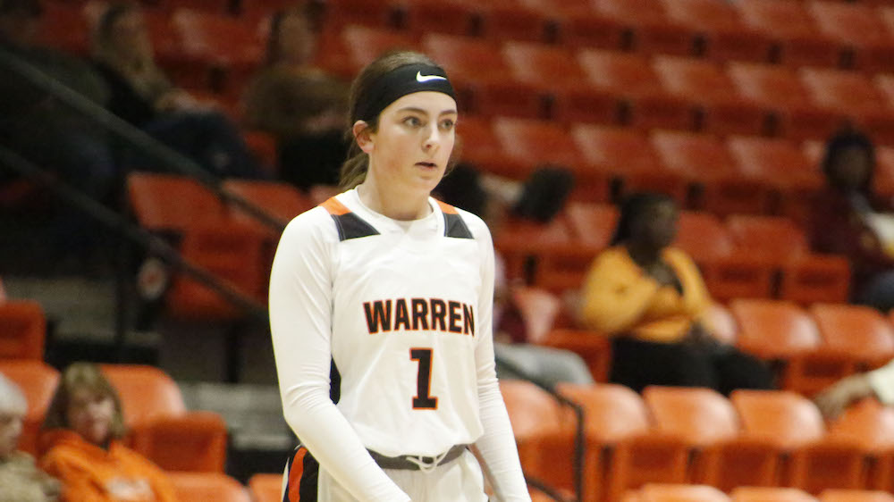 A woman in white and black basketball uniform holding a racket.