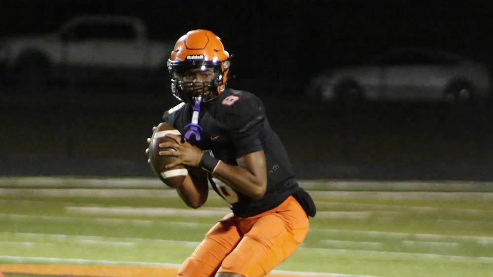 A football player in an orange uniform holding a ball.