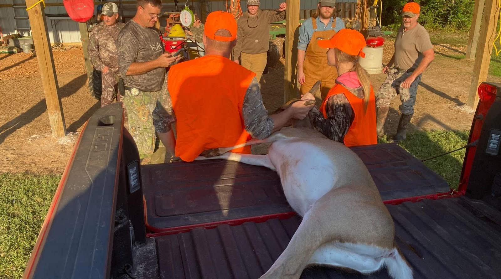 A group of people standing around a dog on the back of a truck.