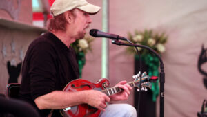 A man playing an instrument while sitting on the floor.