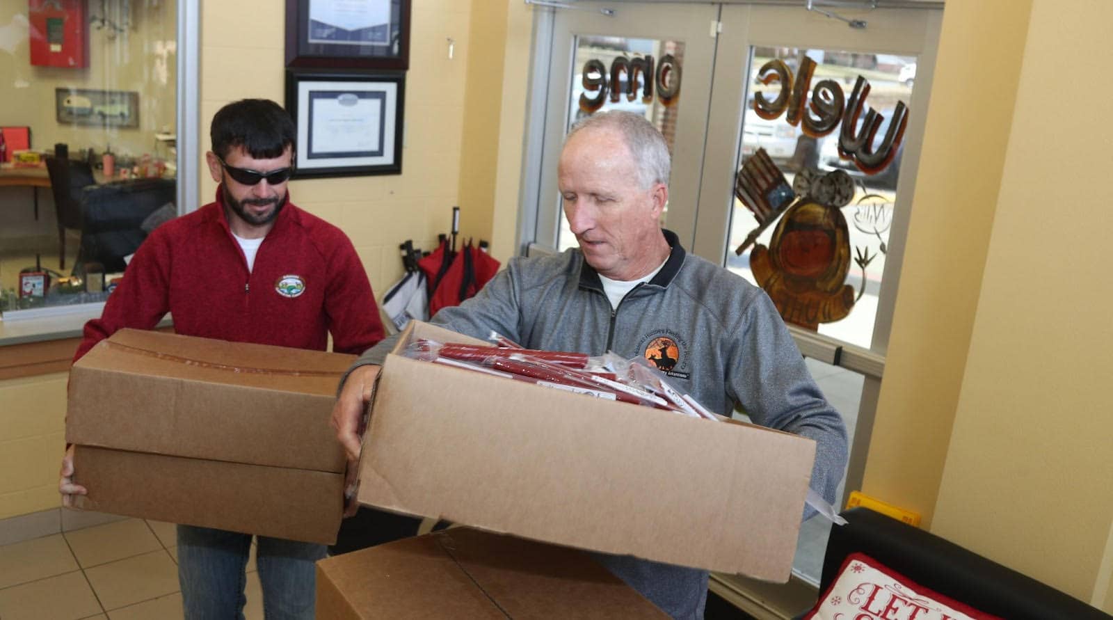 A man holding open a box while another man looks on.